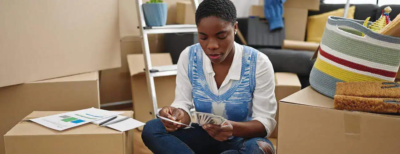 Woman sitting among moving boxes calculating and reviewing moving costs