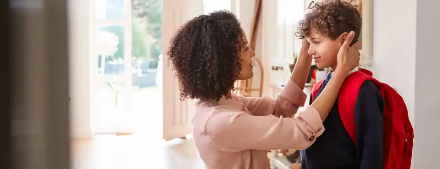 Mother helping child get ready for first day at new school after moving